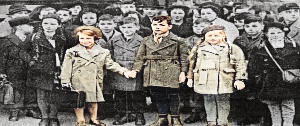 Colourised photograph of children in coats and hats at Waverley Station in Edinburgh, several holding suitcases. Bob McKenzie holds Edith Forrester’s hand, with his sister standing beside him.