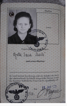 Page from an Austrian passport issued in Vienna in June 1939, with a photograph of a young woman and Nazi eagle stamps.