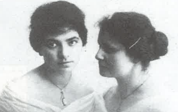 Old black and white studio photograph of two young women, one facing the camera and one in profile.